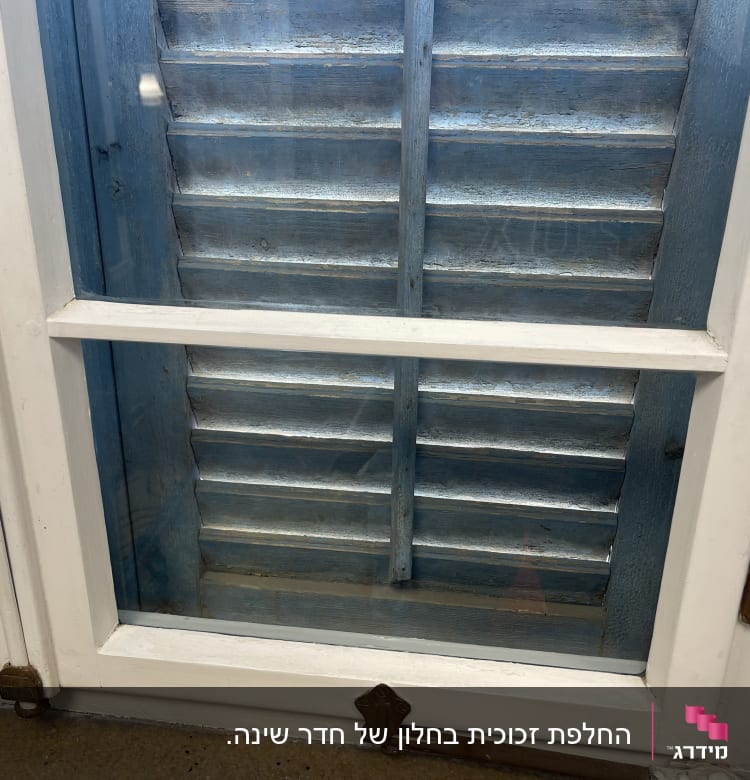 חלון זכוכית עם תריסים כחולים מאחוריו